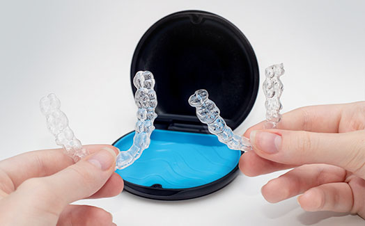 Holding two Invisalign clear aligners