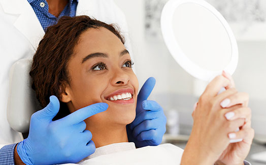 Woman at dentist examining smile in mirror